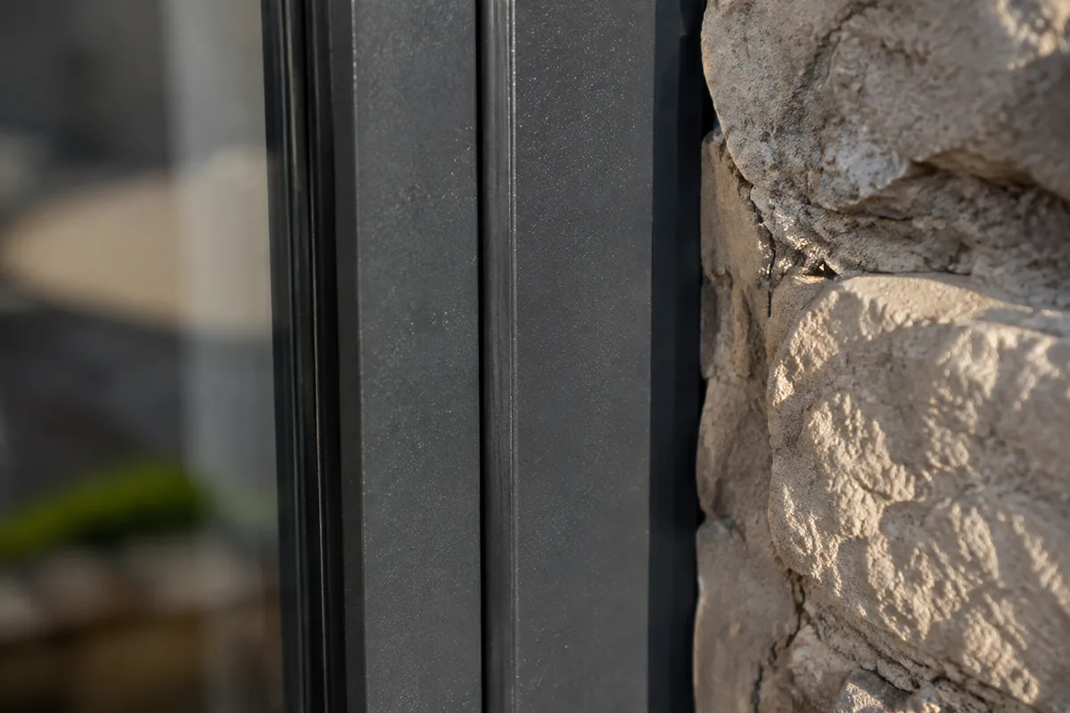 Fenêtre en aluminium laqué gris foncé sur une façade en pierre d&rsquo;un mas provençal