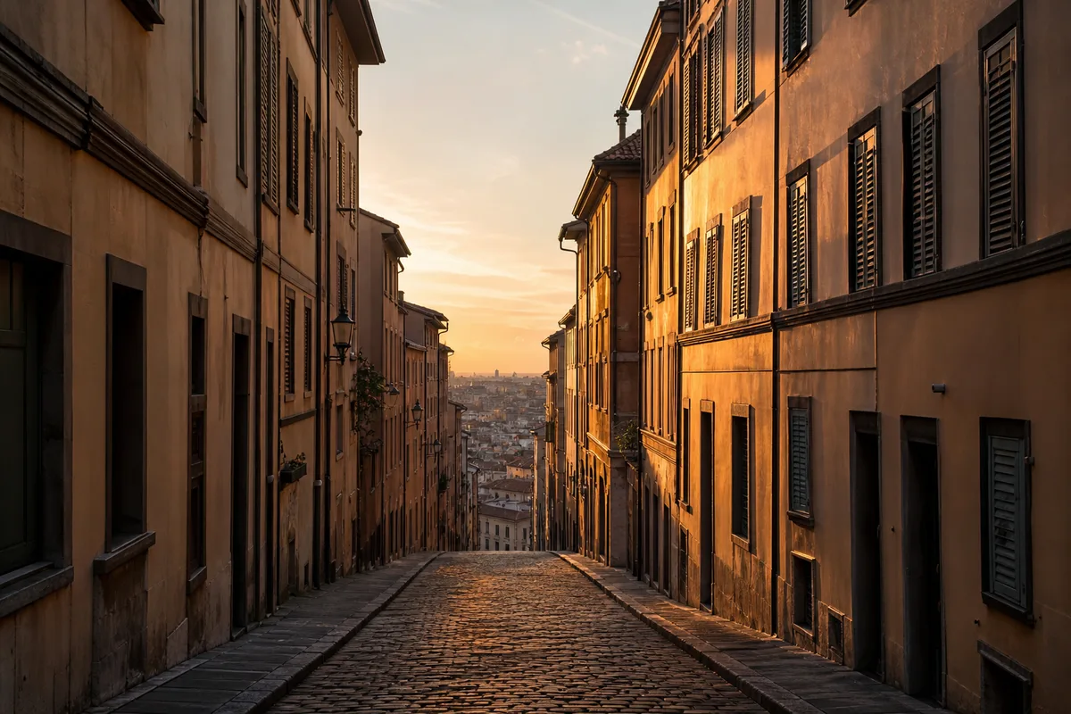 Rue en pente d’un quartier ancien bordée d’immeubles aux persiennes repliées, lumière rasante de fin de journée